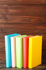 Multi coloured school books on a brown wooden background with copy space. Back to school