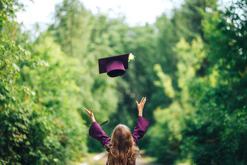 Photo from back graduate graduated little girl in cap throw it up in the sky, happy of ending,...