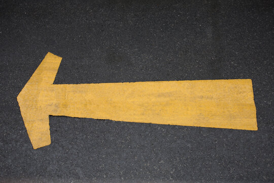 Yellow Arrow Sign On Asphalt Road