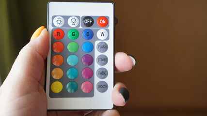 Remote control for change colors in hand on blurred background
