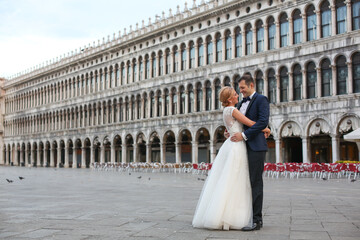 Obraz premium Happy beautiful wedding couple posing in venice square