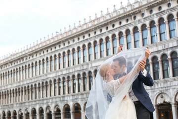 Happy beautiful wedding couple posing in venice square