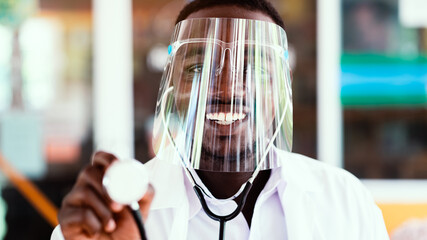 African doctor wear face shield and holding stethoscope with kind and smiling.16:9 style