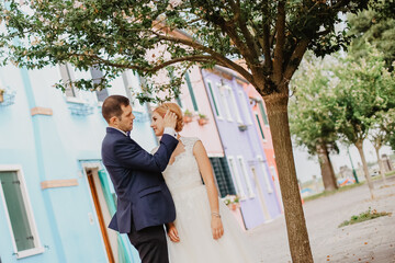 beautiful wedding couple posing under stree near colored houses