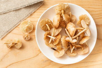 Fototapeta na wymiar Mushrooms on a white plate. A plate of mushrooms stands on a wooden Board, next to the plate is a few more mushrooms