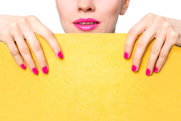 Hand with pink nails holding yellow sheet of pape