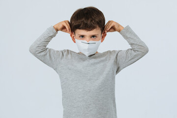 Kid putting on a face mask in a white background