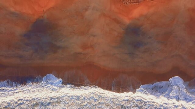 Flying over a sandy beach. Waves break on a sandy beach on the Atlantic coast, aerial View. Nazare, Portugal.