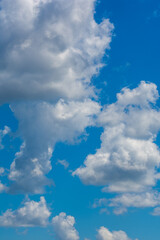 various shape fluffy cummulus clouds accumulating on blue summer sky