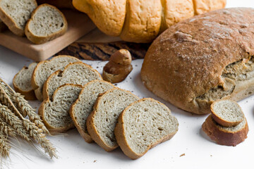 Sliced of whole wheat bread on wwhite with wheat ears.Close up taken