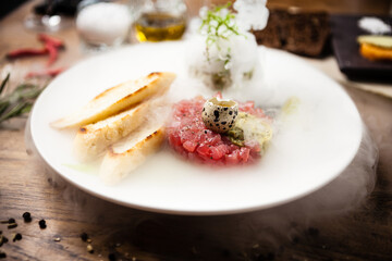 Tuna tartare: Guacamole quail egg baguette on a plate. Delicious healthy raw food closeup served for lunch on a table in modern gourmet cuisine restaurant