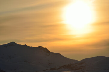Fototapeta na wymiar huge golden sunset over snowy mountain peak background