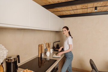 cheerful young woman cutting tasty avocado near cups