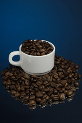White mug with coffee grains sprinkled with coffee grains on a background