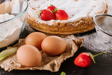 Tasty strawberry pie with ingredients on the black board.