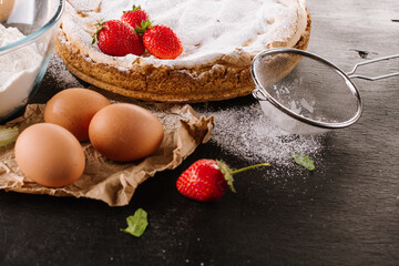 Tasty strawberry pie with ingredients on the black board.