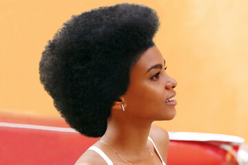 pretty girl with afro hair in front of old red car , havana