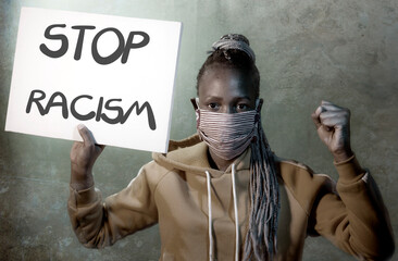 young outraged and hipster African American woman holding protest banner demanding stop racism and racial discrimination