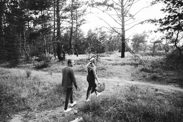 Pregnant girl with a tummy, awaiting delivery, in a red dress and a straw hat with her husband in a field and feather grass