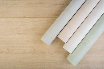 rolls of multi-colored paper wallpaper on a wooden table