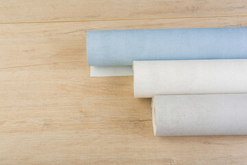 rolls of multi-colored paper wallpaper on a wooden table