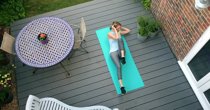 Overhead View Of Healthy Mature Woman At Home Exercising On Deck 