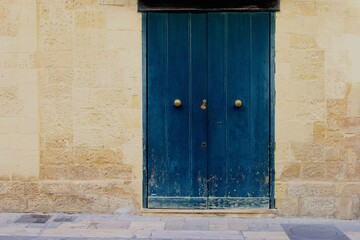 Old blue wooden doors in a natural stone wall, historic town of Lecce, Apulia, Puglia, Italy