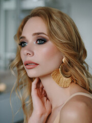Headshot of happy beautiful blonde woman with gorgeous trendy makeup beauty shiny skin posing indoors with natural light