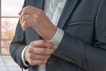 Obraz premium Man buttoning on the sleeves in the office