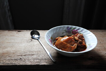 the chicken meat stew in the white bowl on the wooden table during lunch 