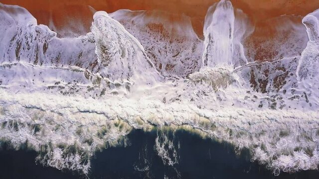 Flying over a sandy beach. Waves break on a sandy beach on the Atlantic coast, aerial View. Nazare, Portugal.