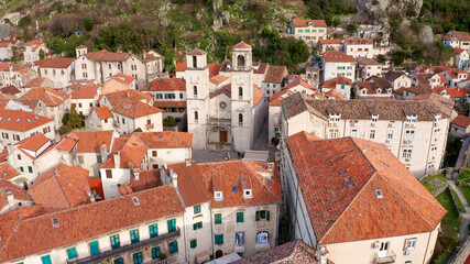 Kotor medieval old town and major tourist destination in Montenegro, featuring The Cathedral of Saint Tryphon from 12th century. Aerial view of vintage stone houses with red roofs, on a sunny day.