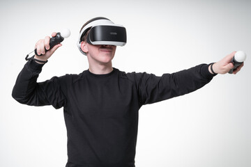 Young man is experiencing VR games with motion controllers and massive glasses, white background studio