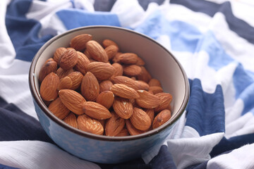 close up of bowl of almond nuts on table cloth 