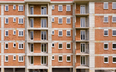 Apartment building under construction: outer wall made of bricks ready for paintwork. Exterior of an unfinished house missing facade.
