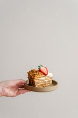 A piece of honey layered cake decorated with strawberries.