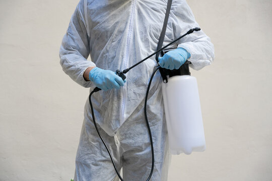 Portrait Of Person Specialized In Disinfestation And Sanitization Of Work Environments Against Coronavirus, Covid-19 - Man With Surgical Facial Mask, Latex Gloves And Overalls, Lance To Spray Liquid