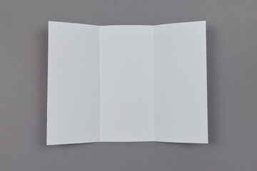 Trifold white template paper on grey background. Copy space. Top view.