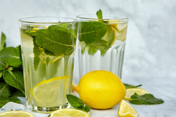 Refreshing drinks for summer, cold sweet and sour lemonade juice in the glasses with sliced fresh lemons. Refreshing summer drink. Traditional lemonade with lemon, mint and ice. Selective focus