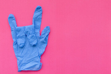 Medical gloves in blue on a pink background show the 