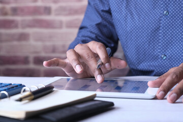 Young man working on digital tablet at office desk, 
