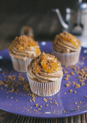 Summer orange cupcakes with marmalade on violet plate.