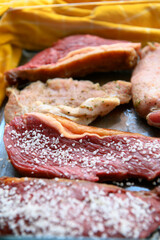 Hand seasoning a piece of raw meat with salt, preparing for a Brazilian barbecue. Selective focus. Flat lay.