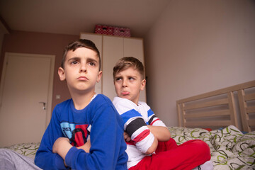 Upset offended brothers is sitting on bed