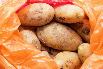 A pile of unwashed potatoes lies in a bright bag