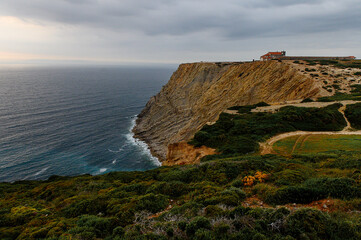 Old church in Portugal on a hill by the ocean at sunset.