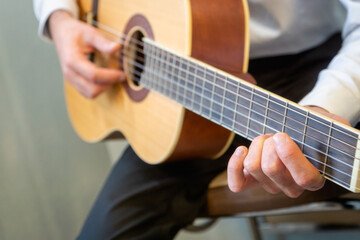 Fototapeta na wymiar Classical guitar - Guitarist playing acoustic guitar in studio - selective focus close-up of the fingerboard and hand 