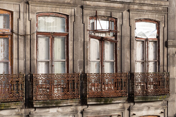 Exterior of a vintage derelict apartment building. Facade of an abandoned historical house in Porto, in need of restoration. False balconies or balconets are common in Portugal.