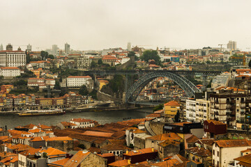 Obraz premium The Dom Luis I Bridge over the Douro River and the colorful houses of Porto Ribeira, traditional facades, old multi-colored houses with red roof tiles on the embankment in the city of Porto, Portugal.