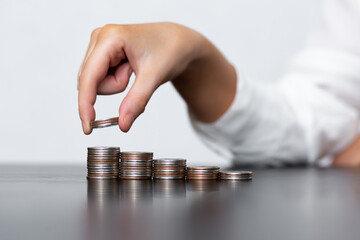 Woman stacks coins in stacks on a black table. The concept of saving money, finance and investment policy.